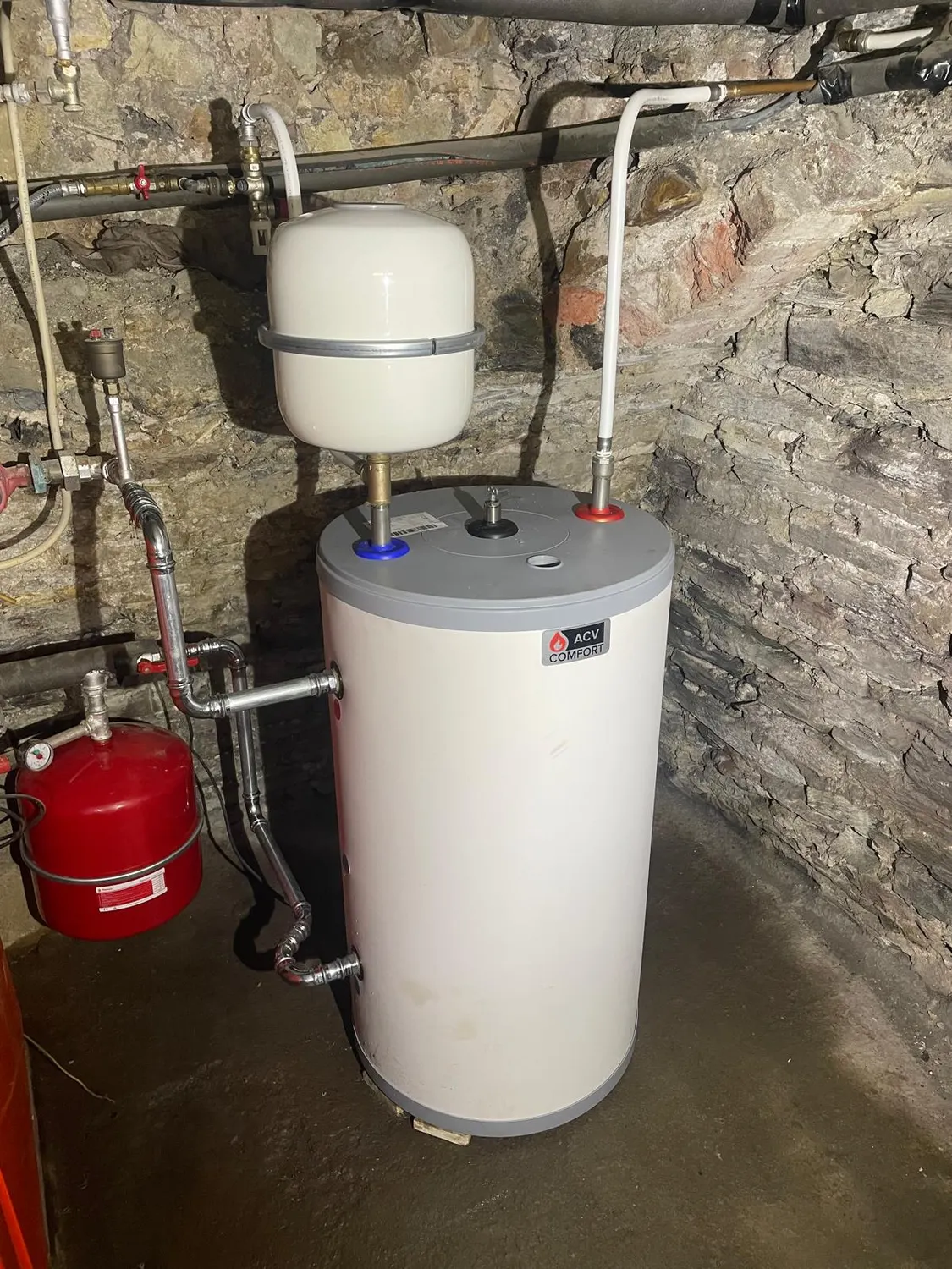 Boiler ACV Comfort neuf dans une cave en pierre, avec vase d'expansion blanc et vase rouge remplacés
