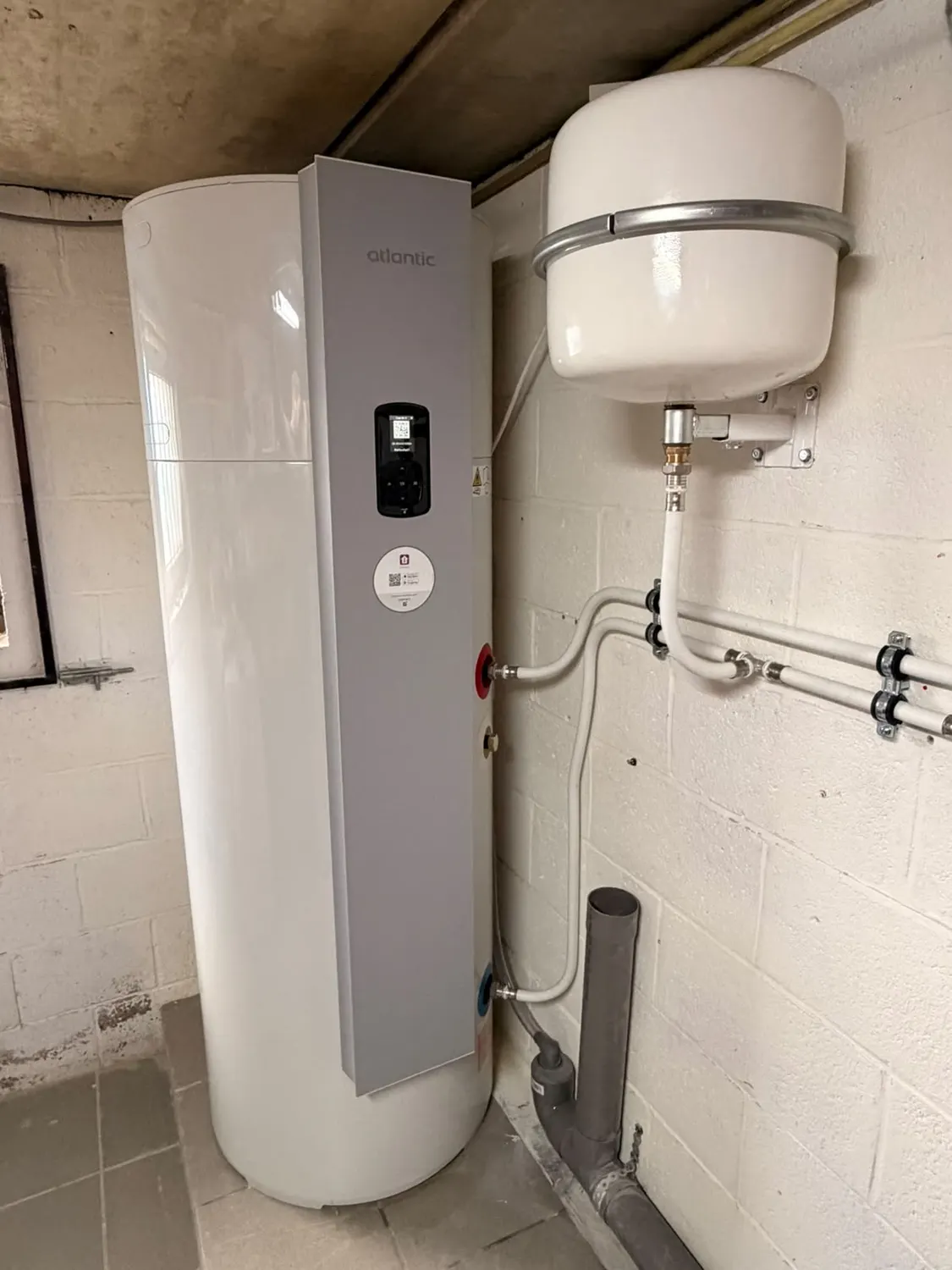 Vue rapprochée d'un boiler thermodynamique Atlantic : commande, raccords eau chaude et eau froide et vase d'expansion