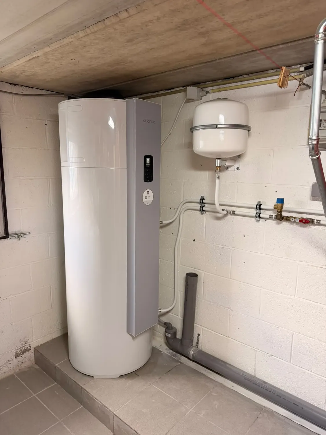 Boiler thermodynamique Atlantic Explorer V5 200 L posé sur un socle, avec vase d'expansion blanc et tuyauterie multicouche