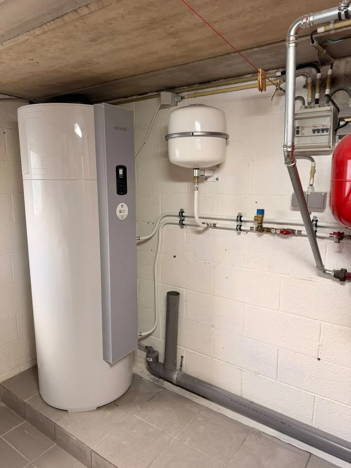 Local technique avec boiler thermodynamique Atlantic, vase d'expansion rouge et tuyauterie de distribution