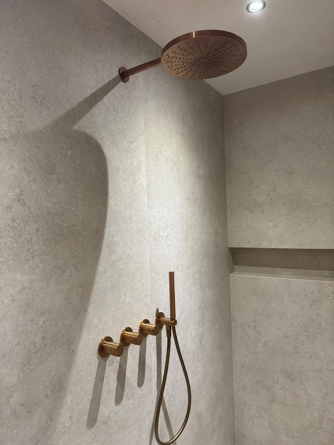 Douche à l'italienne en béton ciré avec niche et robinetterie cuivre
