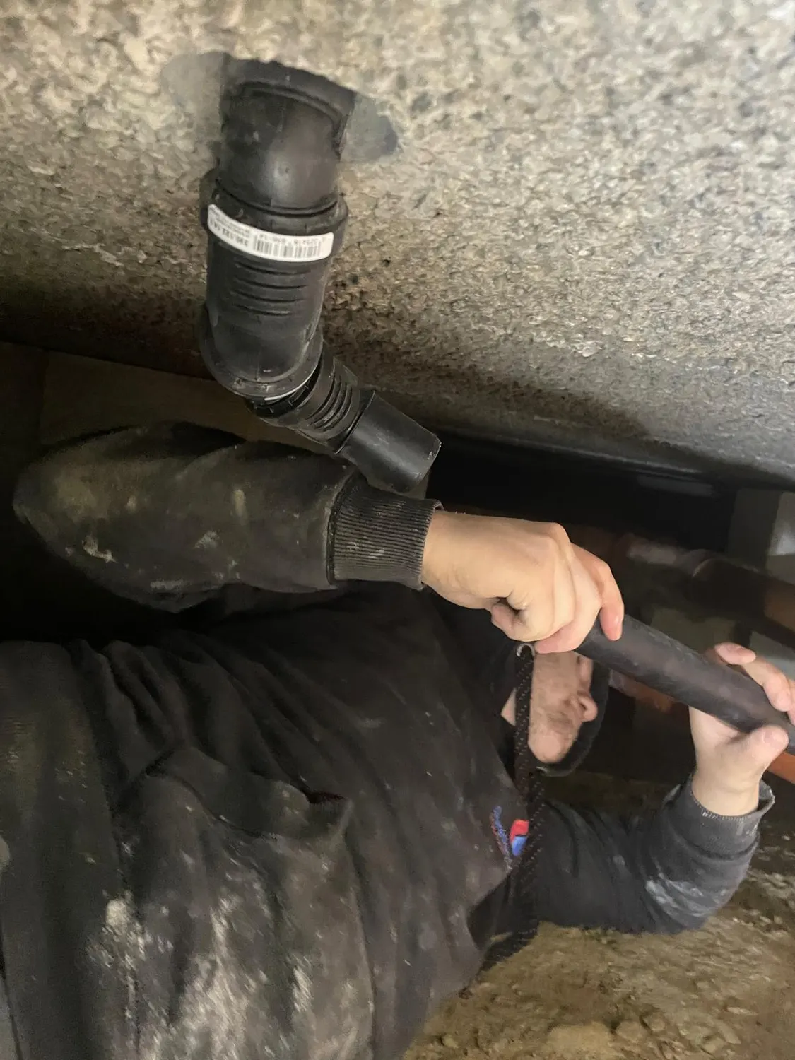 Coude d'évacuation noir fixé sous la dalle, relié à la nouvelle conduite d'évacuation