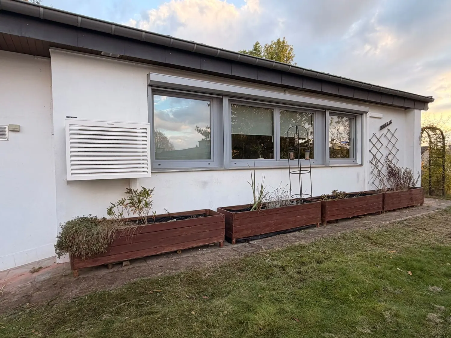 Façade d'une maison à Arlon avec le cache à lamelles blanc qui protège l'unité extérieure de la pompe à chaleur air-air