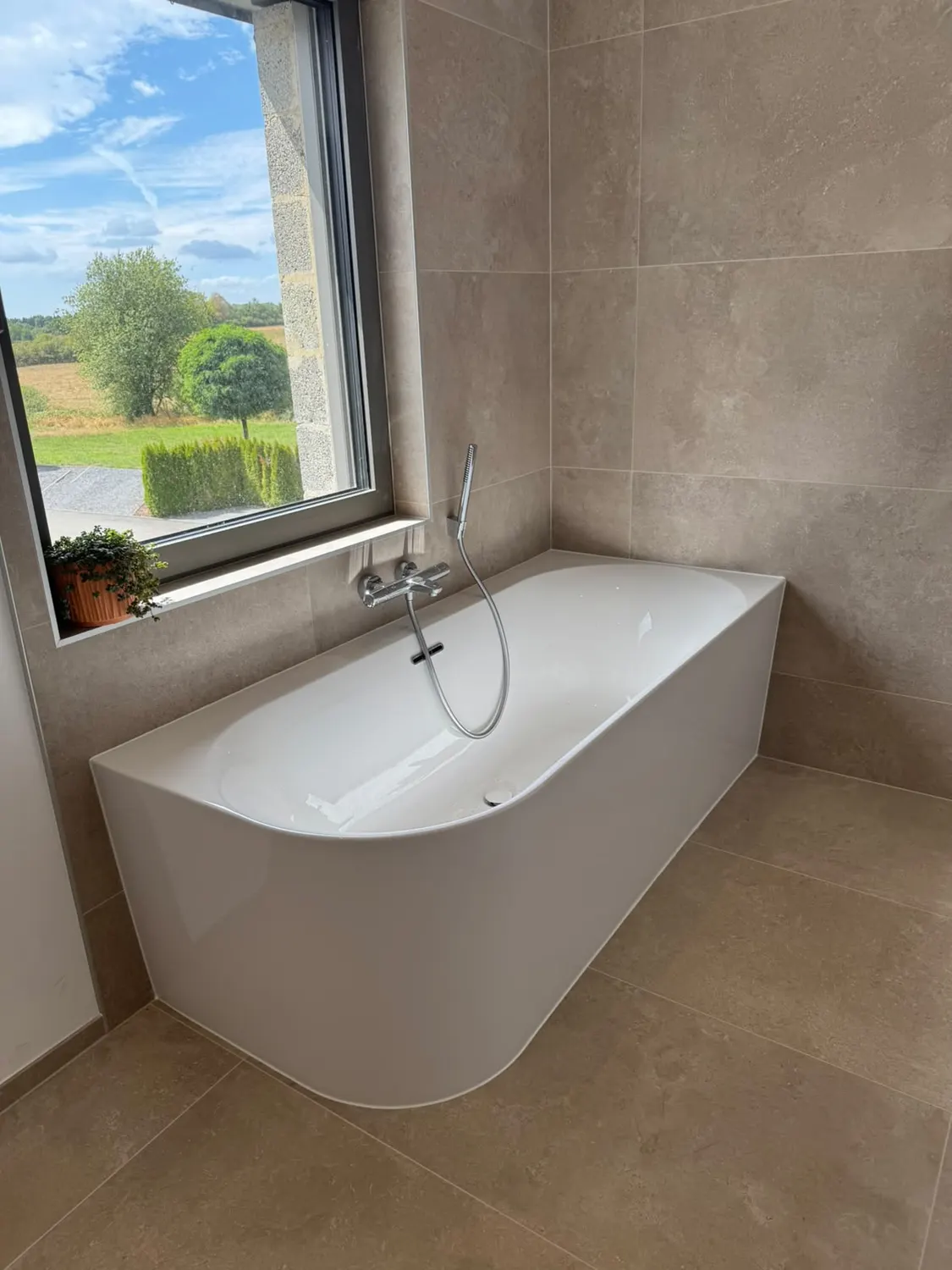 Baignoire îlot près d'une fenêtre dans une salle de bain rénovée