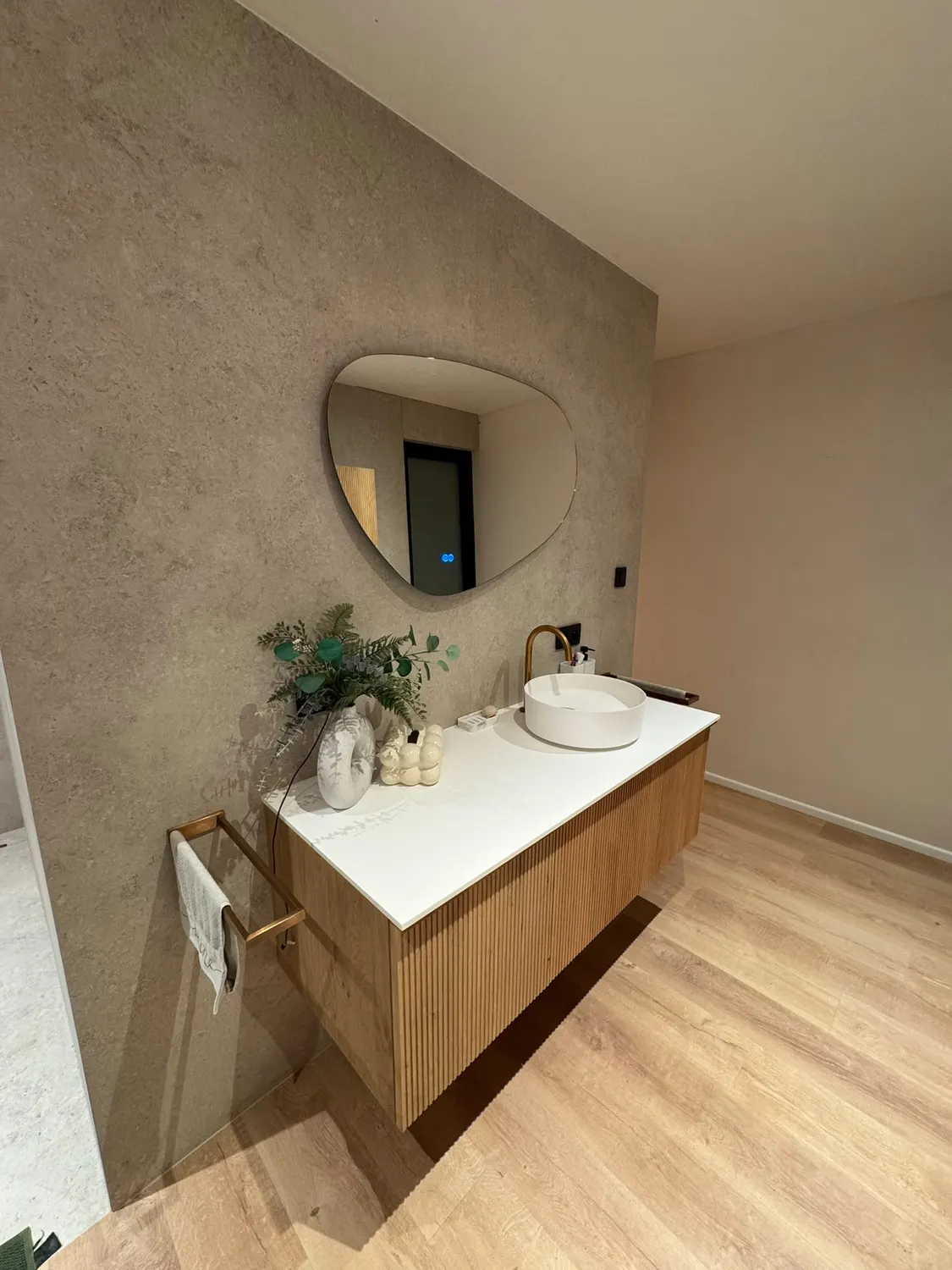Meuble vasque en bois avec miroir et décoration dans une salle de bain lumineuse