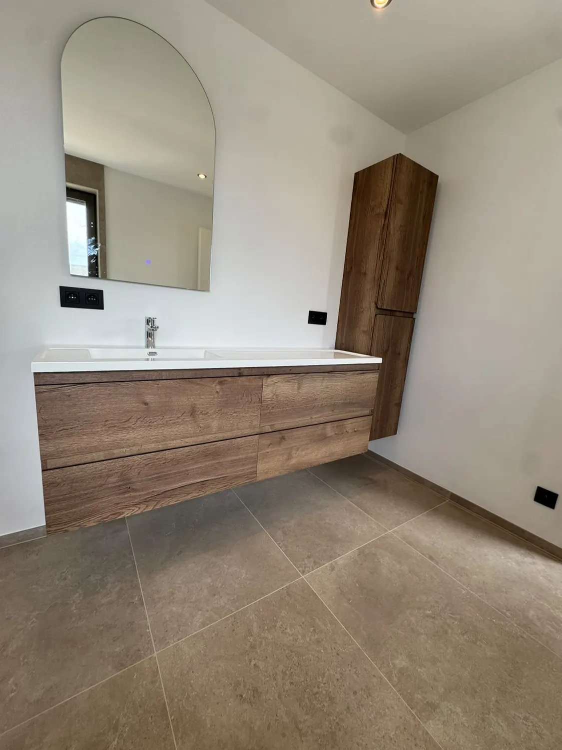 Meuble vasque en bois et grand miroir dans une salle de bain rénovée