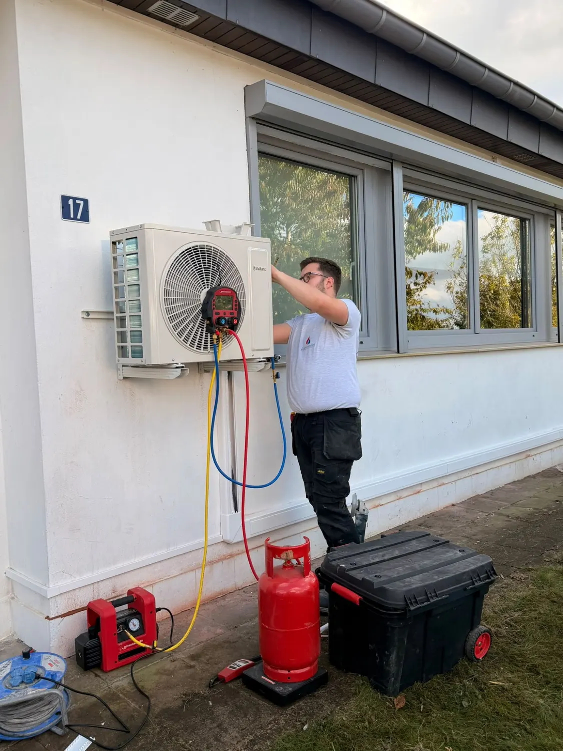 Technicien branchant le manifold, la pompe à vide et la bouteille de gaz pour la mise en service de la pompe à chaleur